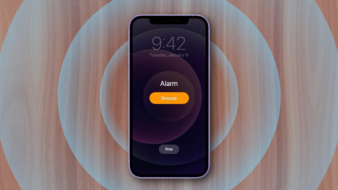 iPhone screen displaying alarm with snooze option on a wooden background, showing time 9:42.